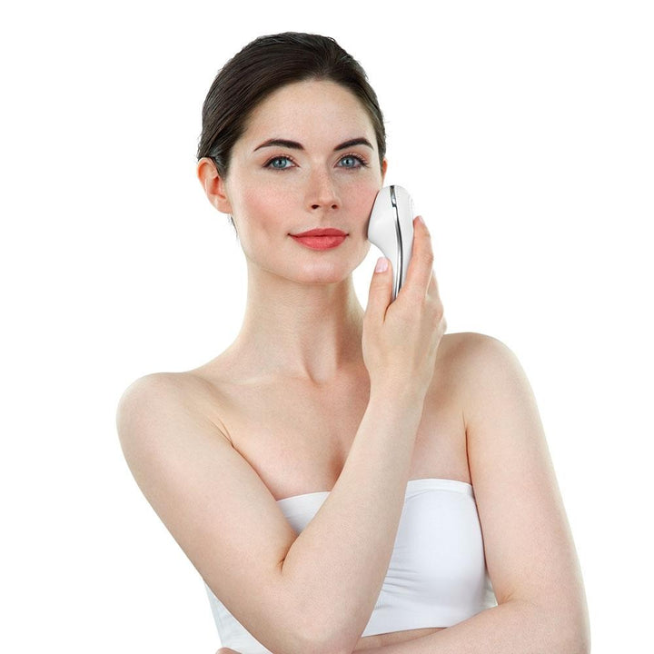 Woman in white holds the Homedics Duo Climate Hot and Cold Sonic Facial Wand to her left cheek