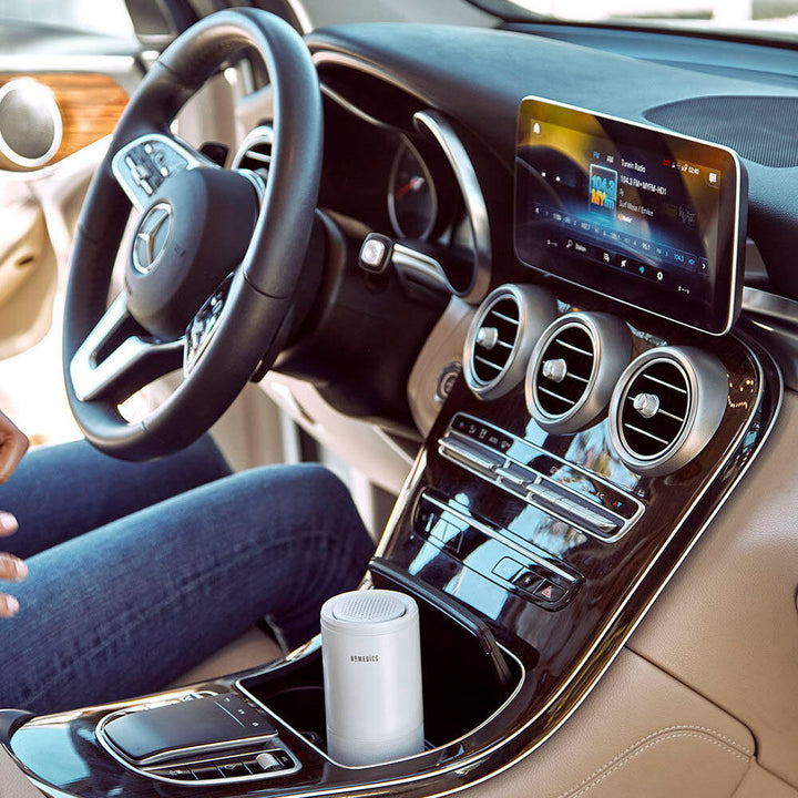 White | Man sits in car with the Homedics TotalClean 4-IN-1 UV Portable Air Purifier in white in cup holder