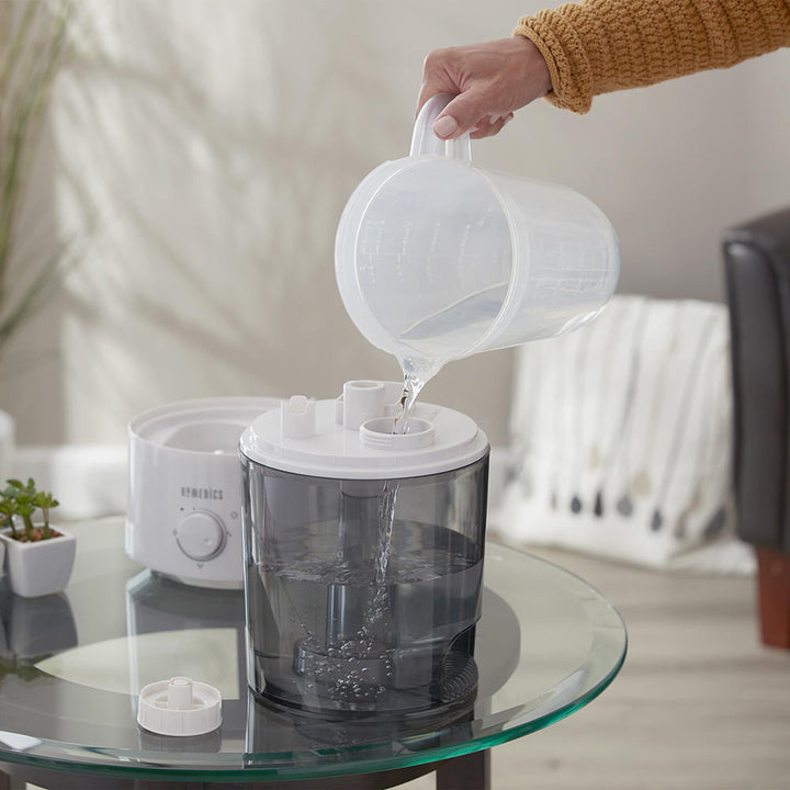 Woman fills tank of the Homedics TotalComfort Adjustable Mist Ultrasonic Humidifier with water