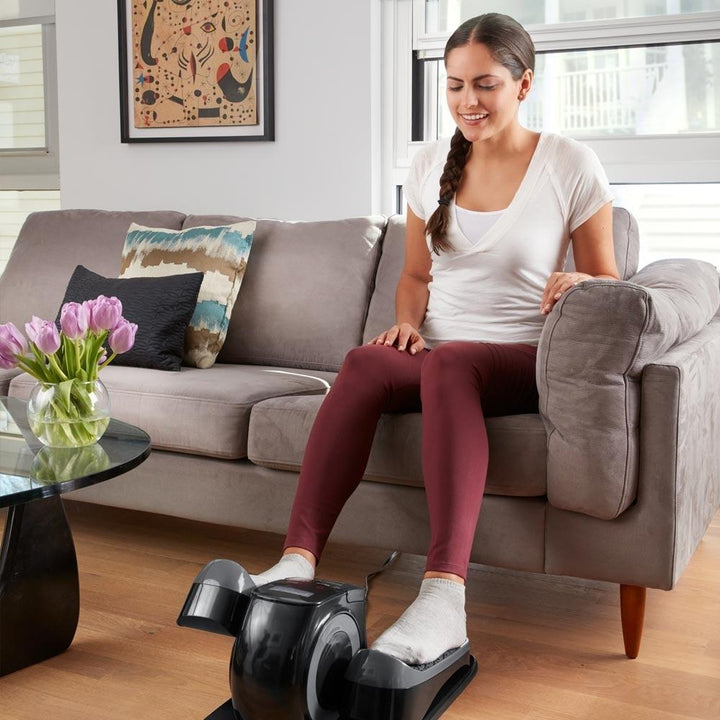 Woman sitting on sofa with feet on the Homedics Stayfit Mini-Stepper