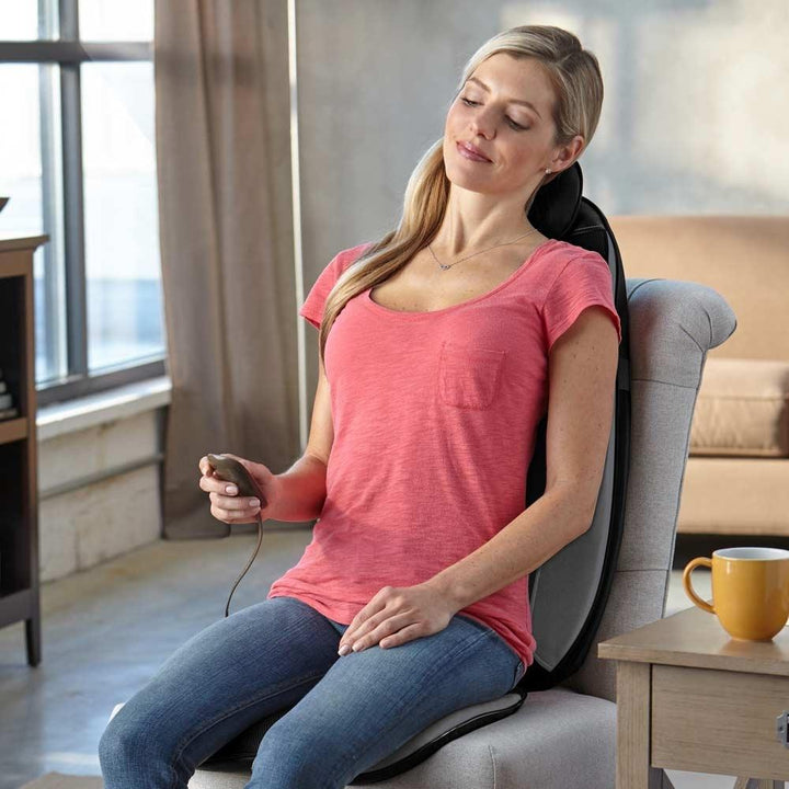 Woman sits on chair and enjoys massage from the Homedics Shiatsu Pro Plus