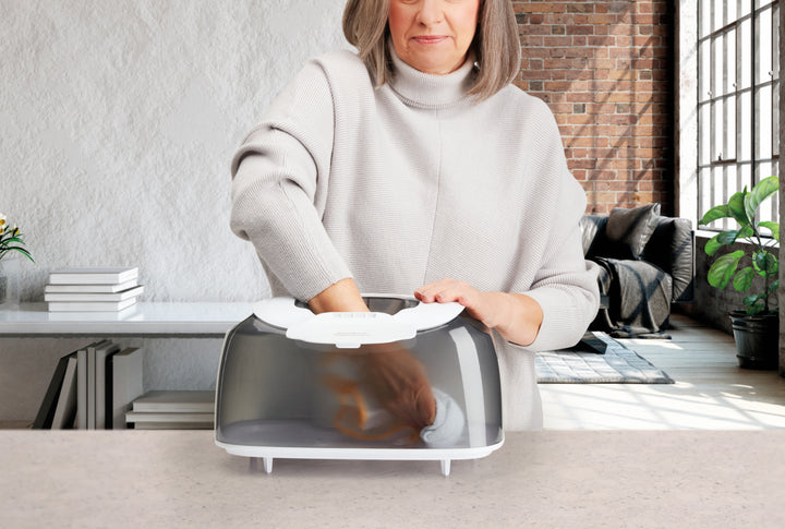 A woman cleans the TotalComfort® Ultrasonic Humidifier with UV-C Technology and Remote Control tank in her kitchen