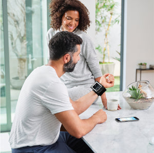 Man sitting at kitchen counter taking blood pressure with Premium Wrist Blood Pressure Monitor with attached Wrist Cuff