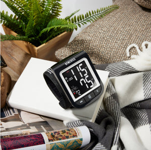 Premium Wrist Blood Pressure Monitor with attached Wrist Cuff placed on book on top of plaid blanket
