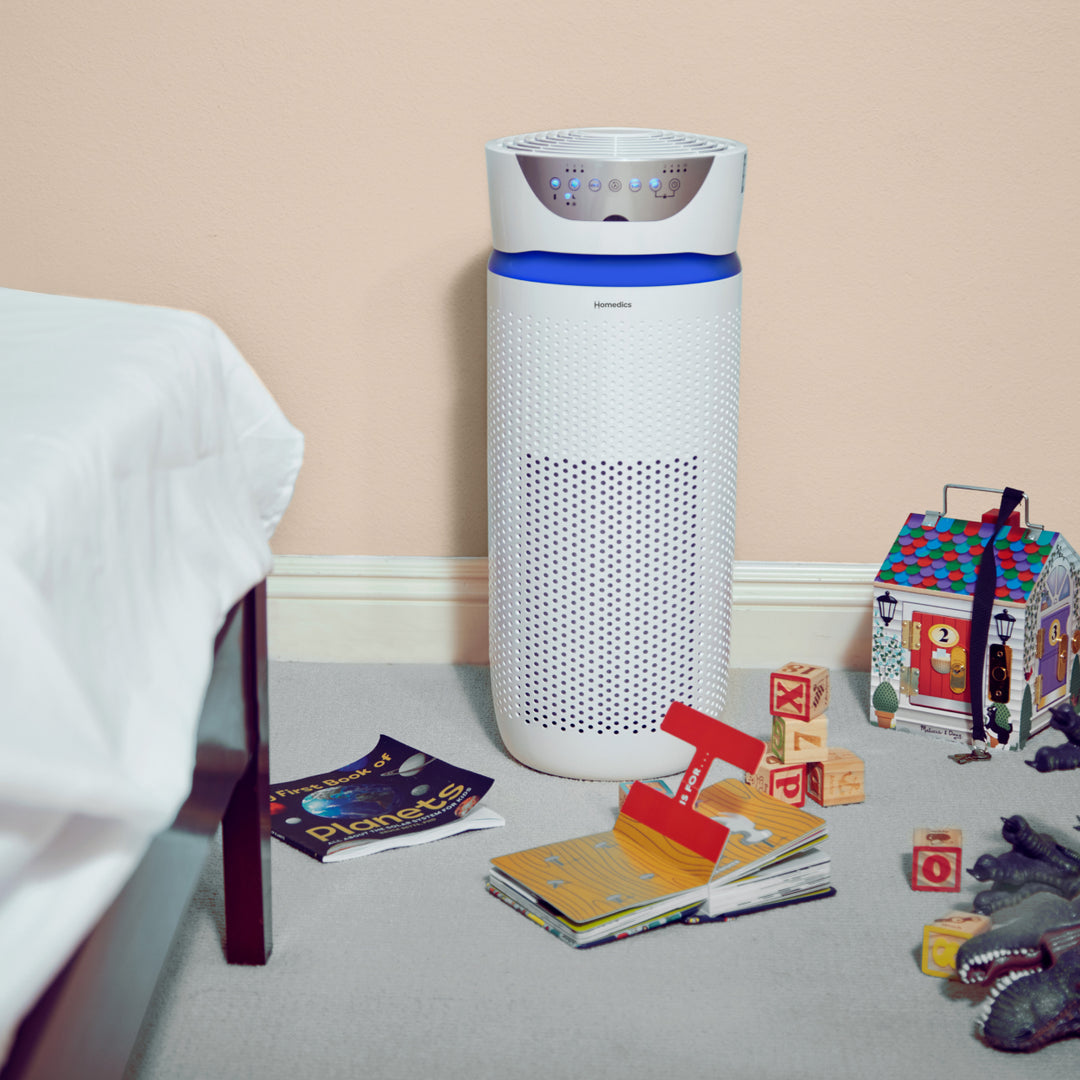 White | Homedics TotalClean 5-in-1 UV-C Deluxe Large Room Air Purifier purifies the air in a child's room with toys and magazines on the floor