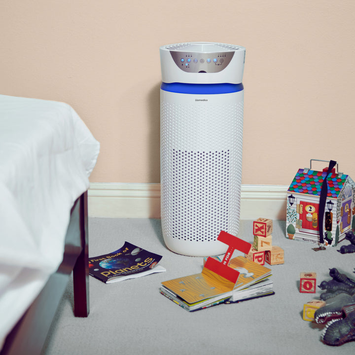 White | Homedics TotalClean 5-in-1 UV-C Deluxe Large Room Air Purifier purifies the air in a child's room with toys and magazines on the floor