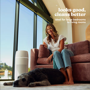 Woman sitting on couch in living room with Dog laying on floor with the Homedics TotalClean PetPlus 5-in-1 Air Purifier