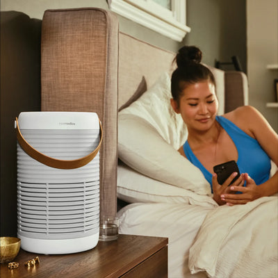 Smart Air Purifier T100 purifies the air while a woman lays in bed and uses her smart phone to access the controls