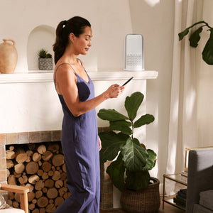 image shows Homedics Air Purifier T12 placed in a room while a person is on mobile phone