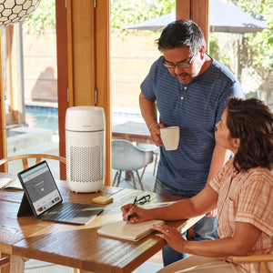 White | Medium Room Tower Air Purifier T22 works in the background as the woman shows her husband something on the laptop