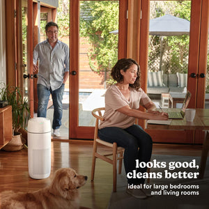 Large Room Tower Air Purifier T43 purifies air in the dining room while a woman sits at the table on her laptop and a dog relaxes on the floor next to her.