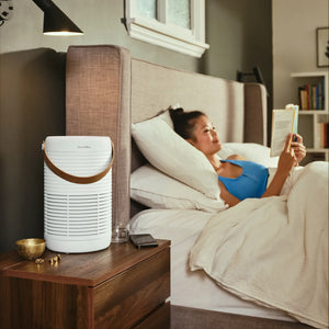 Women reading book on bed while Air Purifier T95 is placed on the side table purifying the room