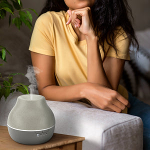 Steam is coming out of Homedics® diffuser and a woman inhales the same for calm experience