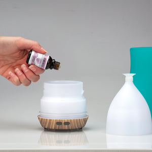 Hands pouring Homedics Lavender Essential Oil into aromatherapy diffuser