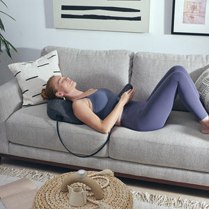 Woman stretches out across couch while laying on the Homedics Body Flex Mini Stretch Mat with Heat