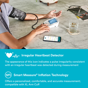 User measures blood pressure with Homedics® 5-Day Trend-at-a-Glance Arm 700 Series Blood Pressure Monitor, One-Touch Use Accurate Results while phone lays on table open to the app