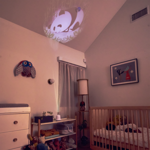 Homedics SoundSpa Lullaby with Sounds & Projection on nightstand with soft light showing a projection image on the ceiling with baby in crib
