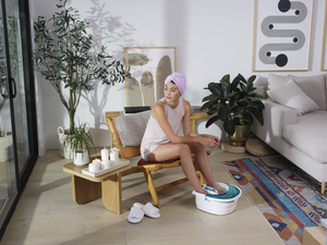 Woman sits in chair relaxing in living room with her feet in the Bubble Spa Elite Footbath