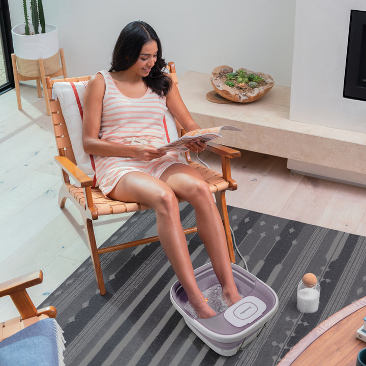 Woman sitting on the chair using the Homedics® Smart Space Deluxe Footbath with Heat Boost