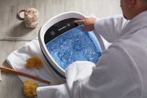 Person adjusting temperature after adding water to the Shiatsu Bliss Foot Spa with Heat Boost