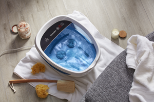 Lifestyle view of Shiatsu Bliss Foot Spa with Heat Boost with loofa, candle, and foot scrubber