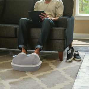 Man sitting on the couch using the Homedics® Shiatsu Air Max Foot Massager