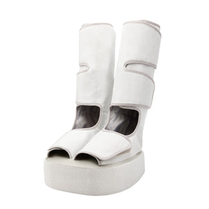 Woman in green leggings sits in chair while wearing the Homedics Real Relief Leg & Foot Massager