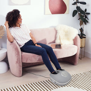 Lifestyle image of woman using the Shiatsu-Air Deluxe Massager with Heat foot massager