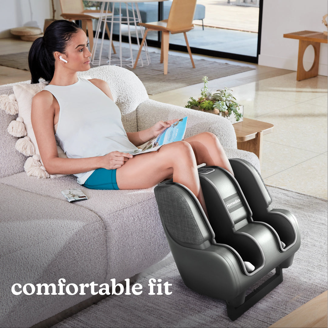 Woman sitting on couch with family while enjoying a massage from the Homedics Deluxe Foot & Calf Massager with Heat