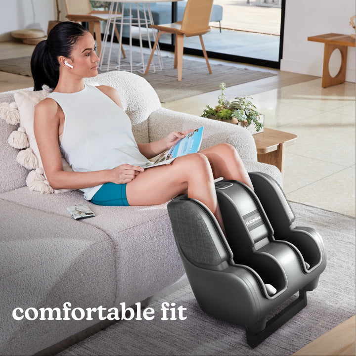 Woman sitting on couch with family while enjoying a massage from the Homedics Deluxe Foot & Calf Massager with Heat