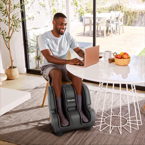 Man sitting on chair while enjoying a massage from the Homedics Deluxe Foot & Calf Massager with Heat