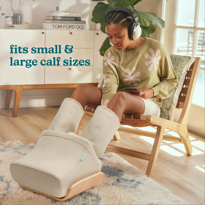 Woman sitting on chair using Homedics® Compression Boot Foot & Calf Massager with Heat.  Massager fits small and large calf sizes