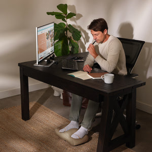 Man sits at office desk reading while enjoying a massage from the Homedics Comfy Footrest Massager