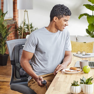 Man works on laptop while sitting on chair with Homedics Contouring Back Support with Soothing Heat attached