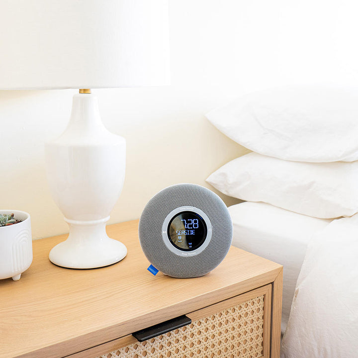 Homedics Deep Sleep Revitalize Engineered Sleep Sound Alarm Clock on nightstand next to bed