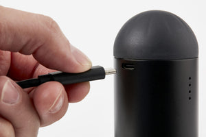Hands inserting USB charging cable into the Homedics Therapist Select Compact Percussion Massager