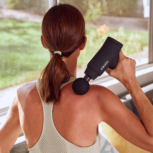 Back view of athletic woman enjoying a right shoulder massage from  the Homedics Therapist Select Plus Percussion Massager