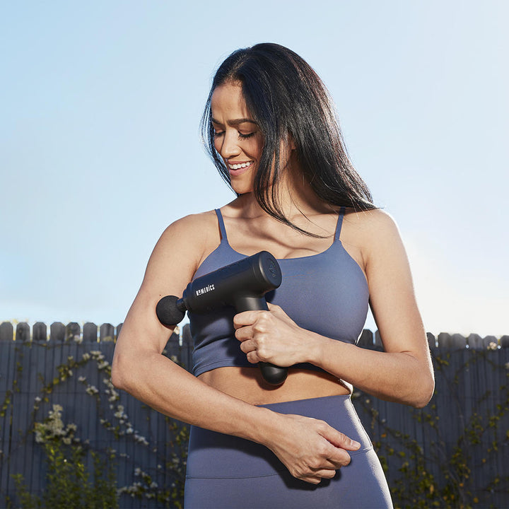 Black | Woman standing outside massages bicep with the Homedics Therapist Select Prime Percussion Massager
