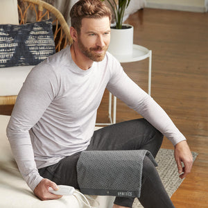 Man sits on the edge of bed with the Homedics 12