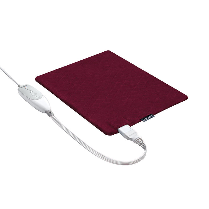 Woman sits on couch with the Homedics 12" x 15" Weighted Heating Pad with Humiditech spread on her right shoulder