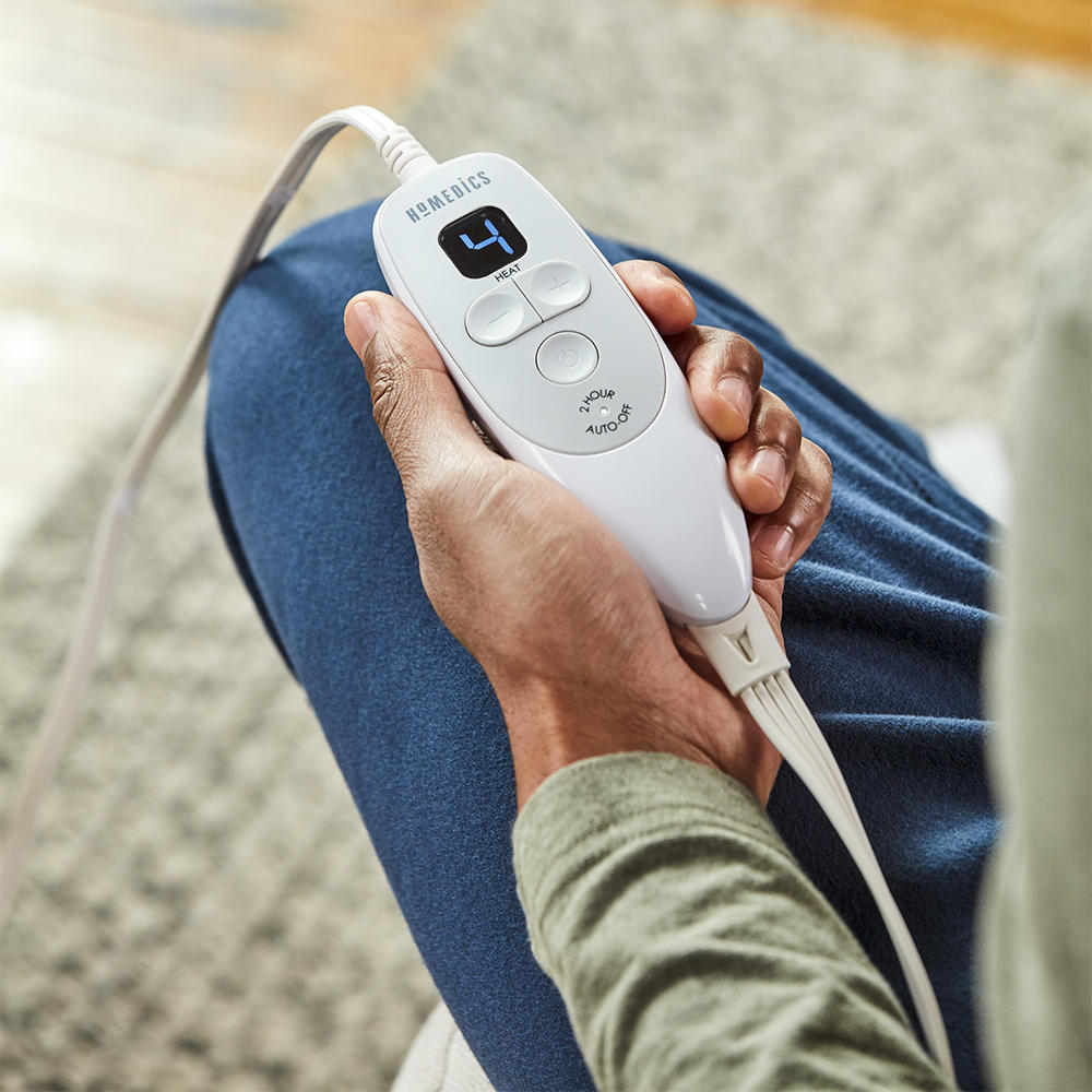 Close-up view of hand holding the LCD controller of the Homedics 12 x 24 Weighted Heating Pad with Humiditech