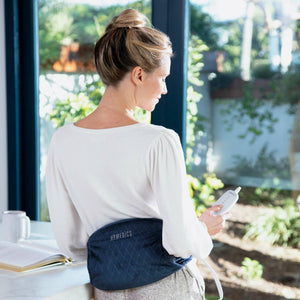 Back view of woman in white shirt standing while wearing the Homedics Women's Health Comfort Heating Belt