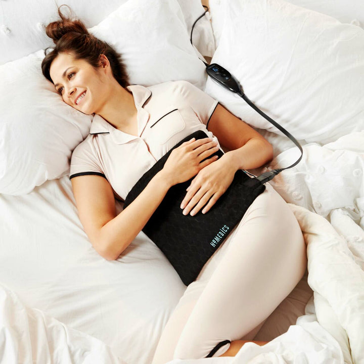 Woman lays across bed with the Homedics 12" x 15" Weighted Gel Heating Pad laying on stomach