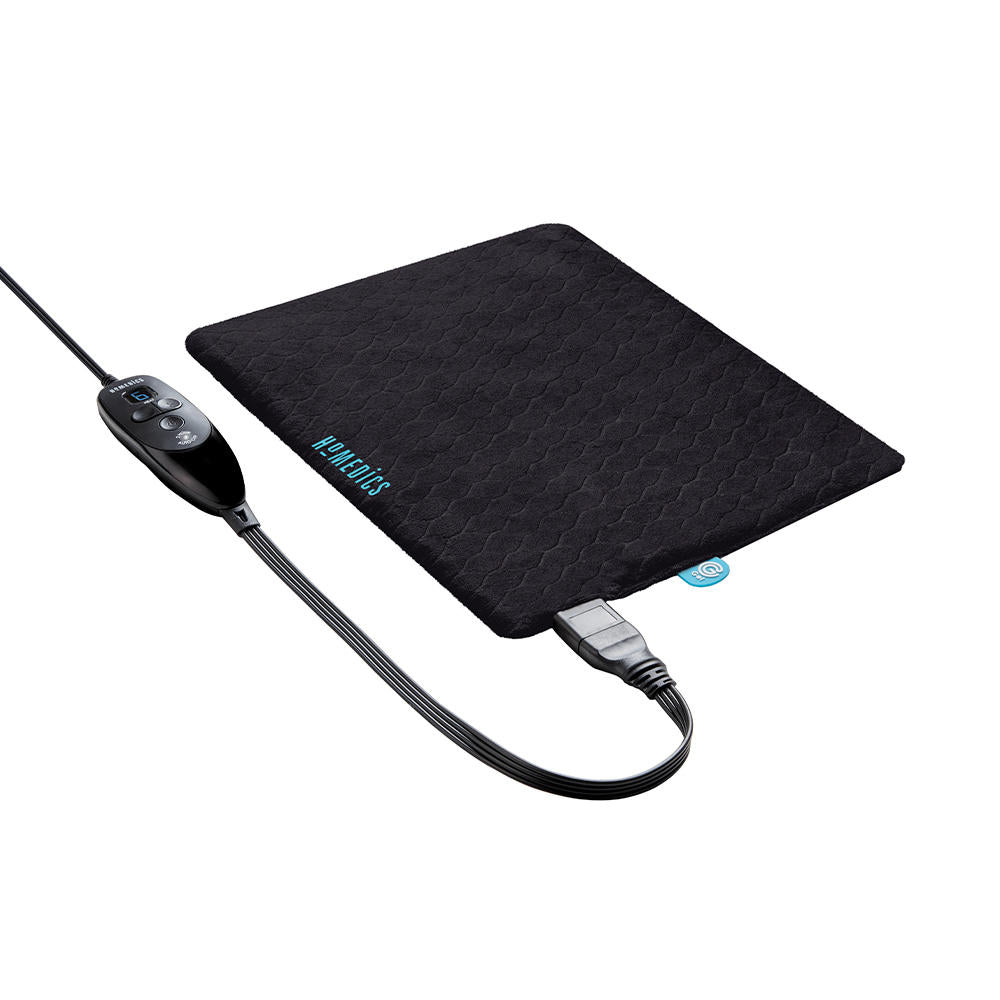 Woman sits on the edge of desk and talks on the phone while holding the Homedics 12" x 15" Weighted Gel Heating Pad against her stomach