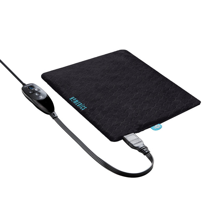 Woman sits on the edge of desk and talks on the phone while holding the Homedics 12" x 15" Weighted Gel Heating Pad against her stomach