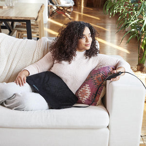 Woman sits in couch with the Homedics 12