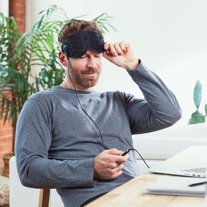 Man adjusts Homedics Gel Eye Mask with Hot and Cold Therapy settings with the mini LED controller