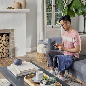 Man sits on couch while the Homedics 12 x 24 Weighted Massaging Heating Pad massages and heats quads