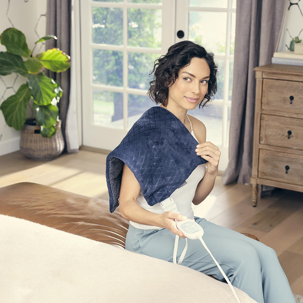 Woman enjoys massage from the Homedics 12 x 24 Weighted Massaging Heating Pad