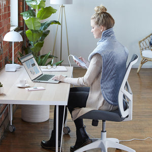 Woman sits in a chair at office desk while enjoying a massage from the Homedics XL Massage Wrap with Heat Massage